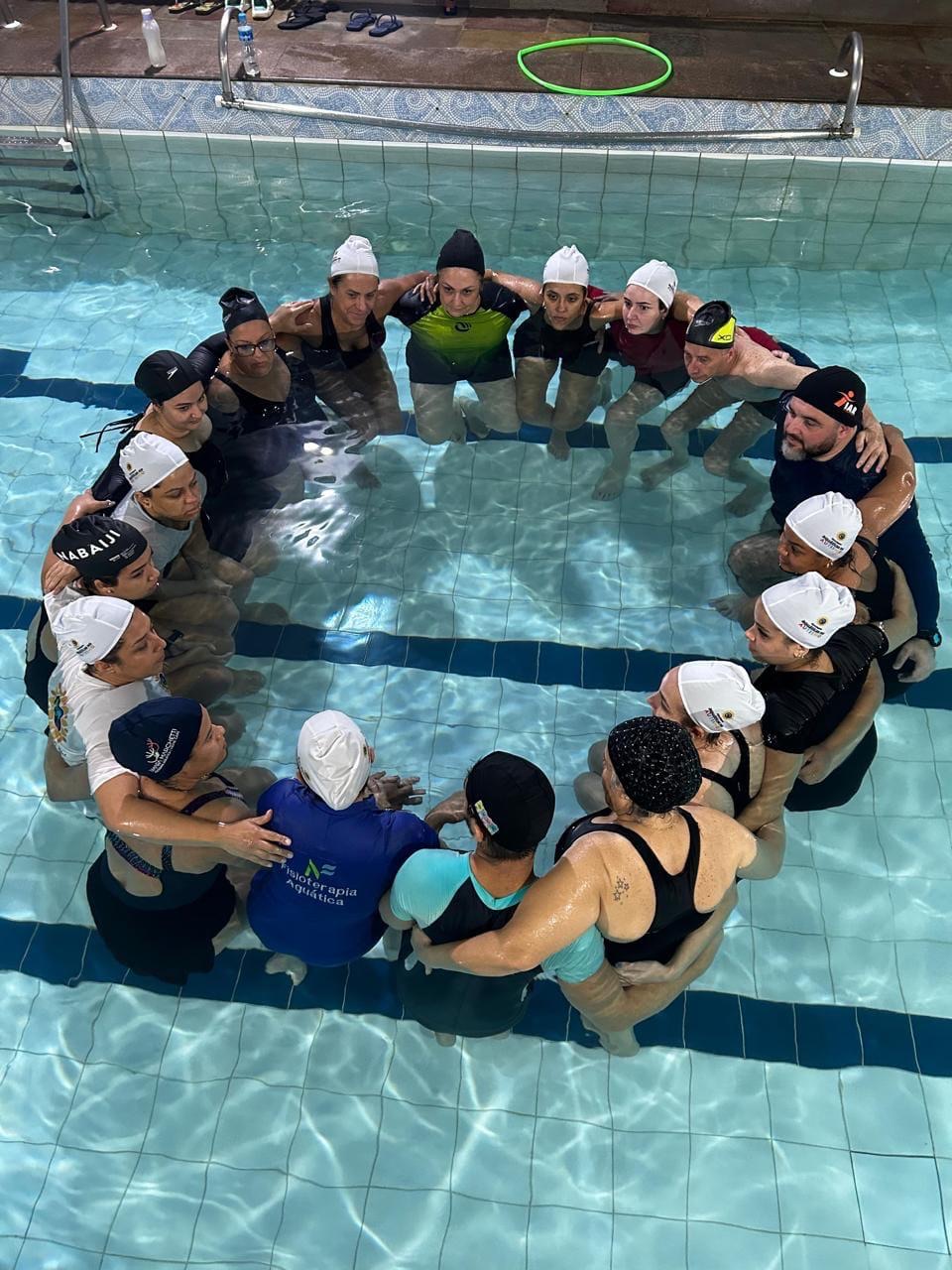Turma abraçada em roda dentro da piscina, vista de cima